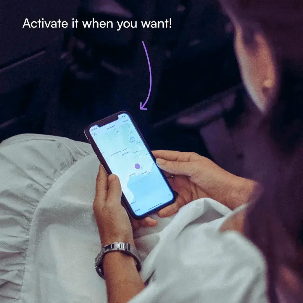 Person using a smartphone with an app on it, sitting in a car at night.